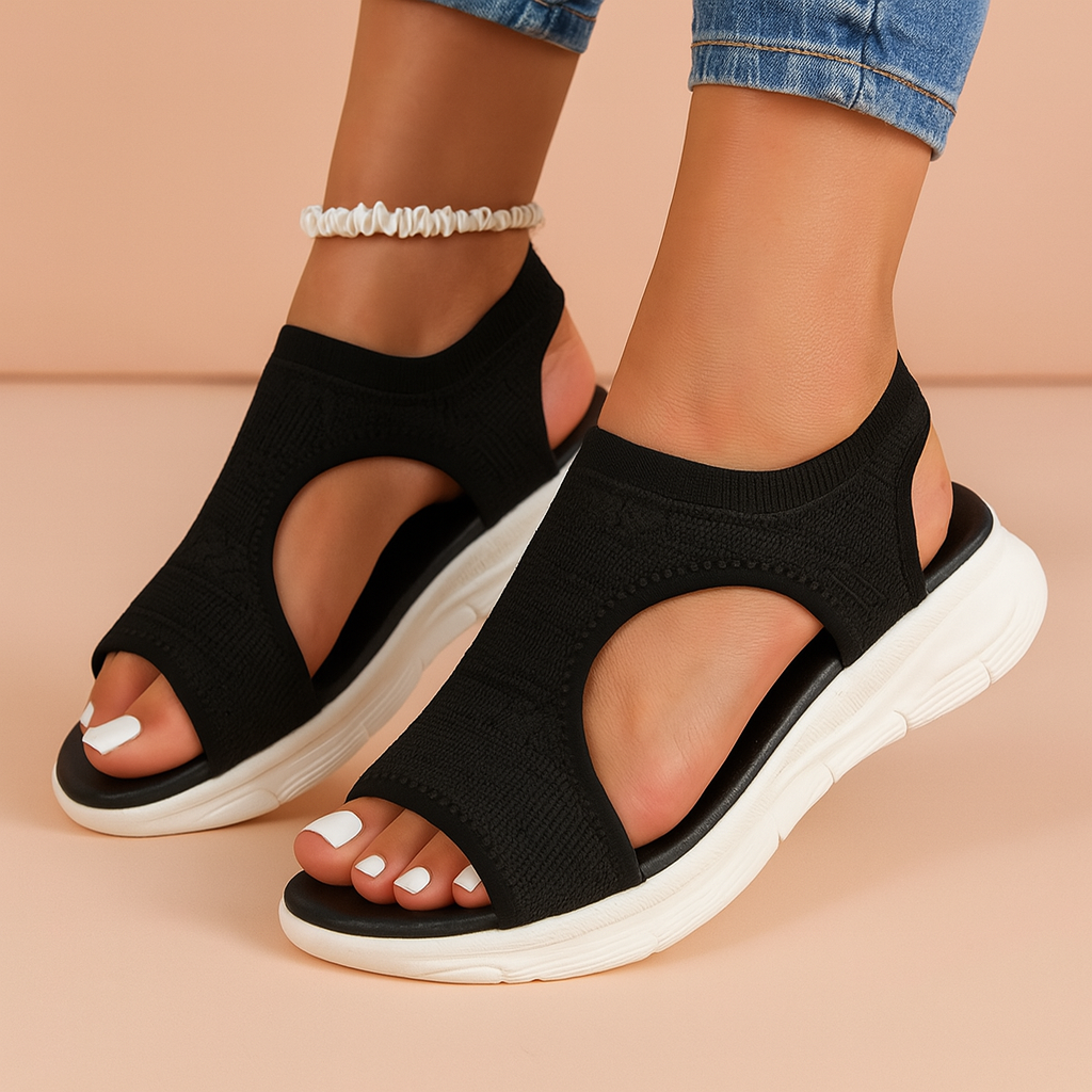 Zwarte orthopedische sandalen van gebreid materiaal met open zijkanten en gewatteerde witte zolen, bieden ademend comfort en ondersteuning van de voetboog voor dagelijks gebruik.