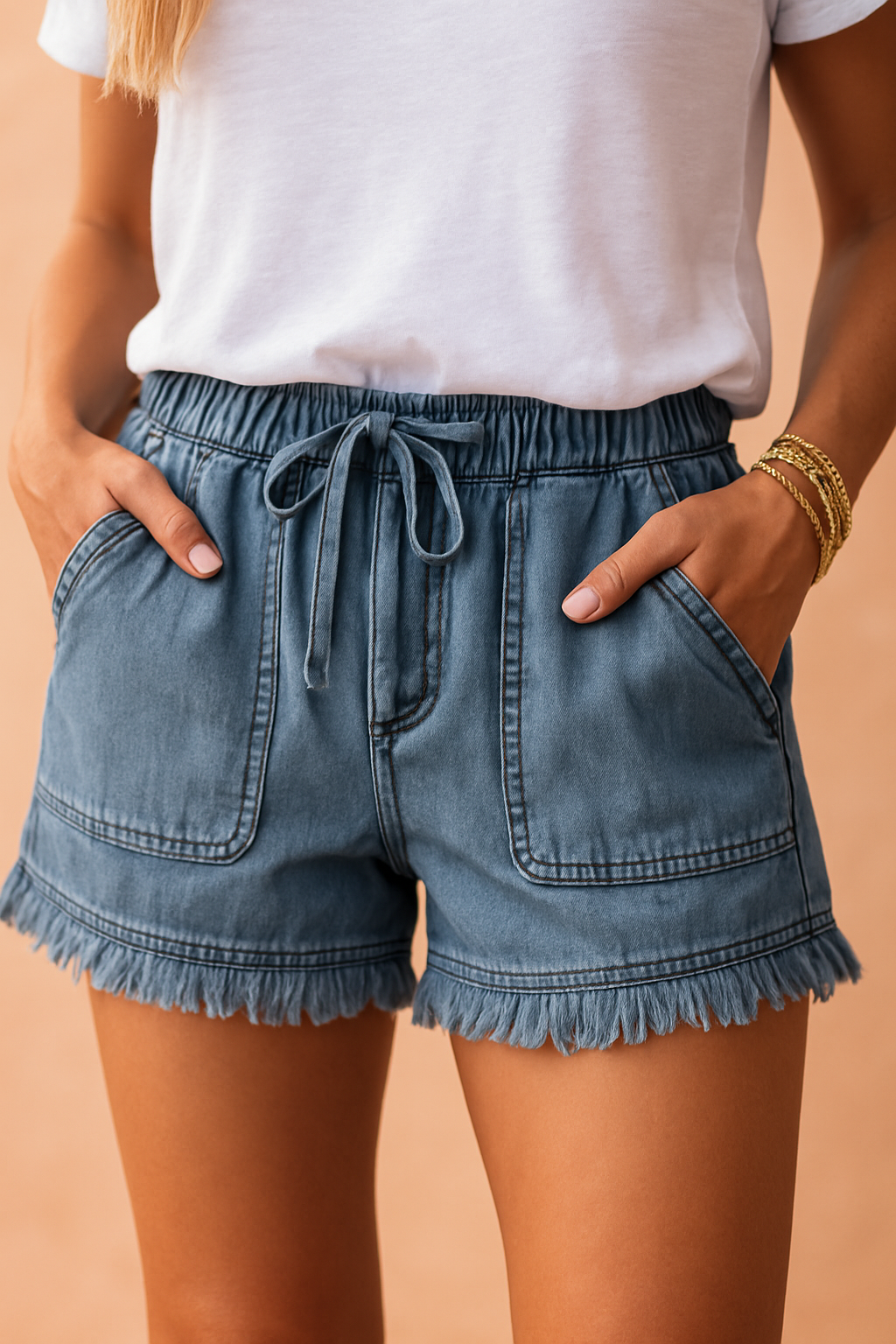 Blauwgewassen high-rise denimshorts met rafelzoom, oversized opgestikte voorzakken en verstelbare tailleband met trekkoord—de perfecte mix van comfort en casual stijl.