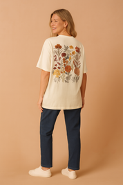 Crèmekleurig dames T-shirt met een ronde hals en korte mouwen, voorzien van een geborduurd borstzakmotief met gedetailleerde bloemenprint in aardetinten. Het shirt heeft een losse, comfortabele pasvorm van zachte katoenen jersey, ideaal voor casual outfits.