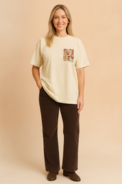 Crèmekleurig dames T-shirt met een ronde hals en korte mouwen, voorzien van een geborduurd borstzakmotief met gedetailleerde bloemenprint in aardetinten. Het shirt heeft een losse, comfortabele pasvorm van zachte katoenen jersey, ideaal voor casual outfits.