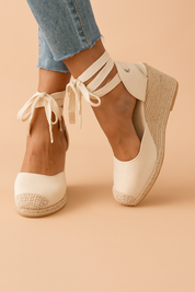 Espadrille-wedge met gevlochten plateauzool en wikkelbanden rond de enkel, ideaal voor zomerse outfits en comfort.