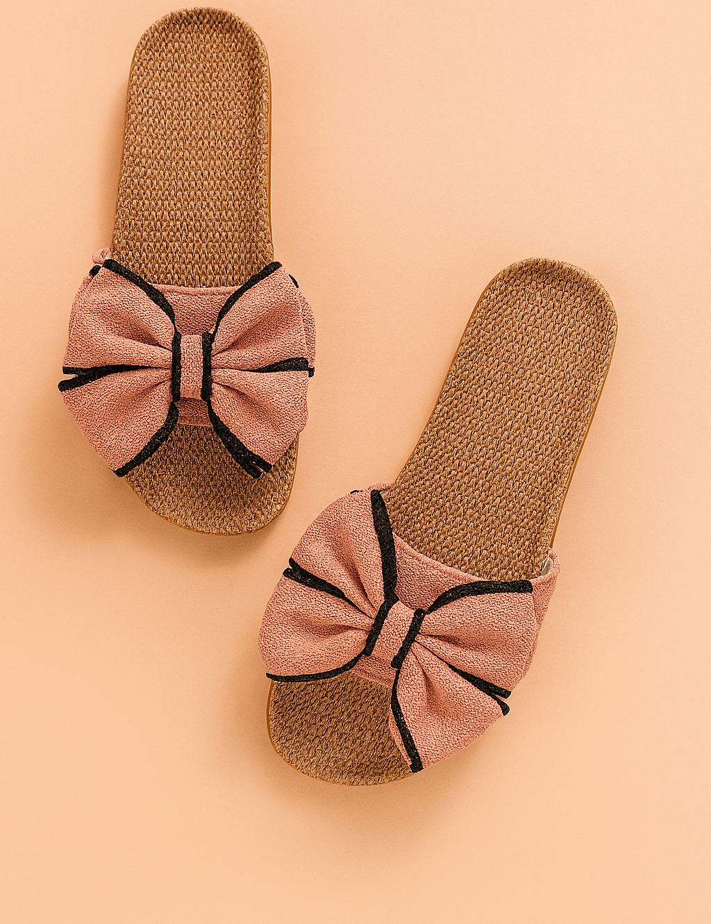 Geweven instapsandalen met oversized roze stoffen strikken en opvallende zwarte accenten, combineren comfort met speelse elegantie voor de zomer.