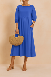 Kobaltblauwe midi-jurk met 3/4-mouwen, hoge taille en losvallende pasvorm in effen stof.