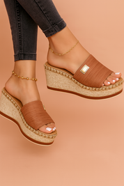 Sleehak sandaal met gevlochten platformzool en brede instapband met goudkleurig detail, perfect voor casual en zomerse styling.