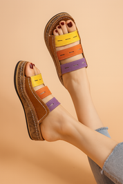 Opvallende kleurrijke platform sleehak sandalen met bruine lederen look en bandjes in geel, oranje en violet—stijlvol en comfortabel voor warme dagen.