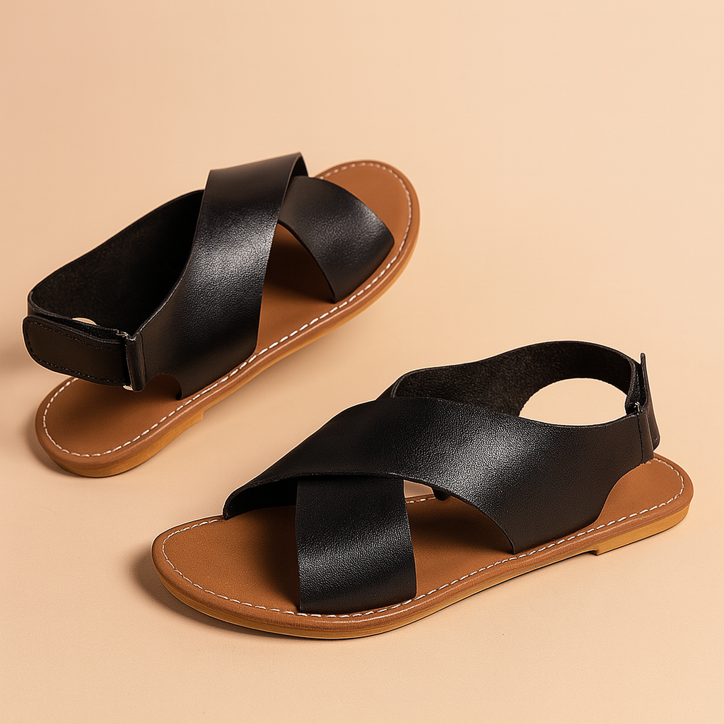 Zwarte klassieke platte sandalen met brede gekruiste leren bandjes en amandelbruin voetbed—stijlvol en moeiteloos te combineren.